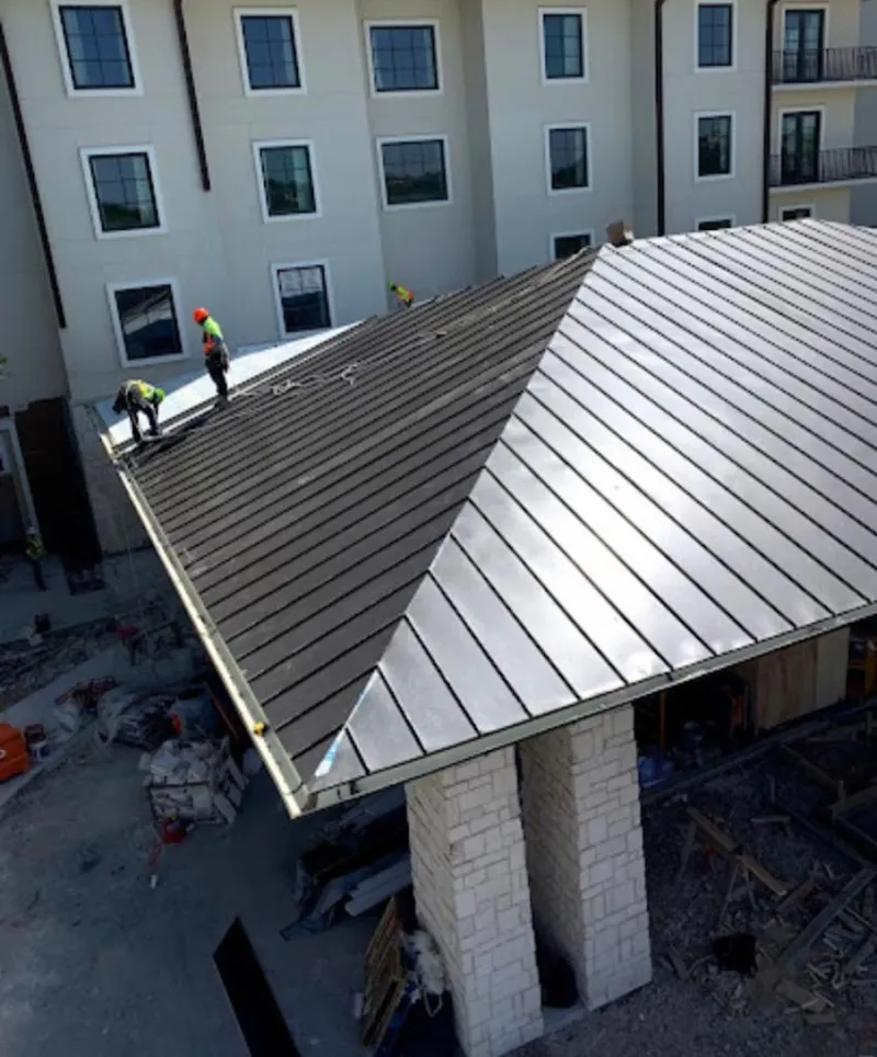 Crew installing standing seam metal roof panels on a commercial project in Douglas